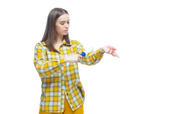 Retrato de mulher jovem usando um removedor de fiapos para limpar camisa xadrez amarelo de poeira, cabelo, fiapos e cotão, isolado no fundo branco — Fotografia de Stock