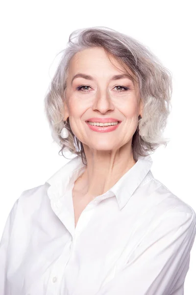 Närbild porträtt av trevlig gråhårig medelålders kvinna tittar på kameran med ett brett leende och visar lycka, isolerad på vit studio bakgrund — Stockfoto