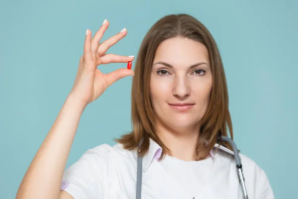 Жінка-лікар показує ліки на синьому фоні. Копіювати вставку. концепція охорони здоров'я . — стокове фото