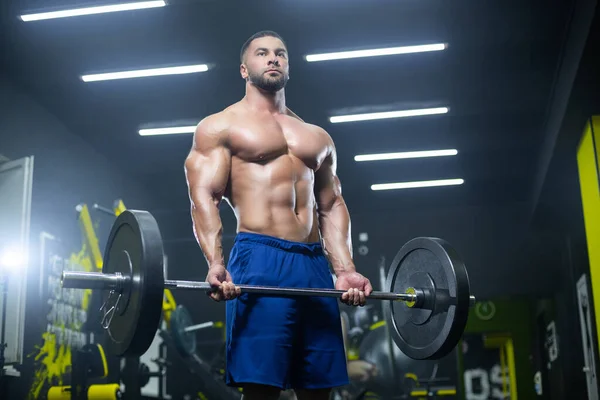 体操で彼の筋肉を示す重い鐘を持ち上げる筋肉運動選手の下のビュー — ストック写真