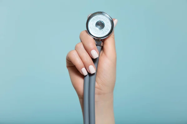 Main d'une femme médecin avec un stéthoscope, sur fond bleu. Copier la pâte. concept de santé. Image En Vente