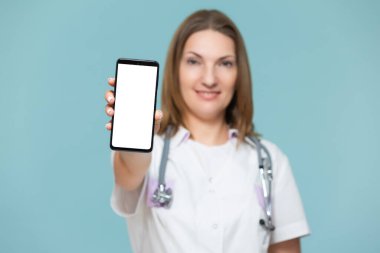 Mavi arka planda akıllı telefonu olan bir kadın doktor. Reklam için yer var. Kopyala yapıştır. sağlık hizmeti kavramı.