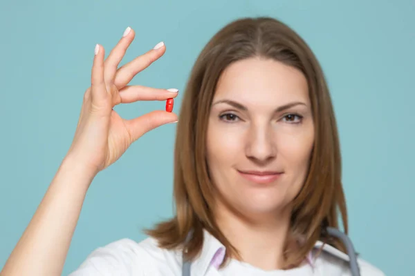 Woman doctor shows medication, on a blue background. Copy paste. healthcare concept. Royalty Free Stock Images