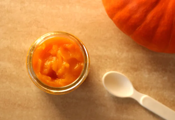 Baby pumpkin puree in a glass jar with a white spoon — Stock Photo, Image