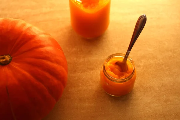 Baby pumpkin puree in a glass jar with a spoon and fresh pumpkin — Stock Photo, Image