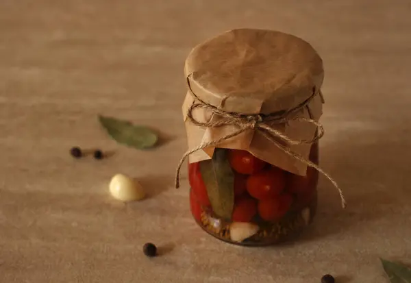 Tomates rojos en escabeche en un frasco de vidrio con pimienta, ajo y laurel — Foto de Stock