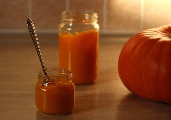 Baby pumpkin puree in a glass jar with a spoon and fresh pumpkin — Stock Photo, Image