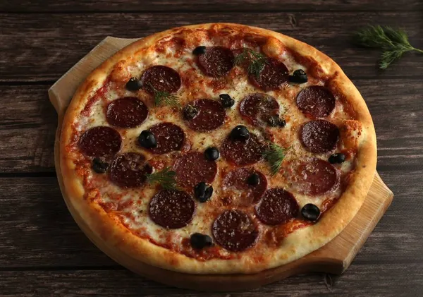 Siyah ahşap arka planda sosisli ve zeytinli biberli pizza.