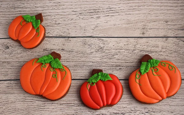 Gingerbread hand-painted in the form of pumpkins on a light wooden background — Stock Photo, Image