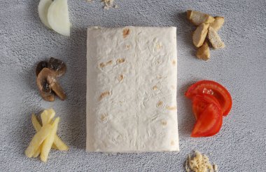 Patatesli pita ekmeği, domates, mantar, soğan, peynir, gri arka planda et. en üstteki görünüm