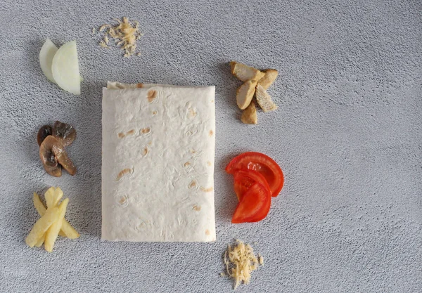 Patatesli pita ekmeği, domates, mantar, soğan, peynir, gri arka planda et. en üstteki görünüm