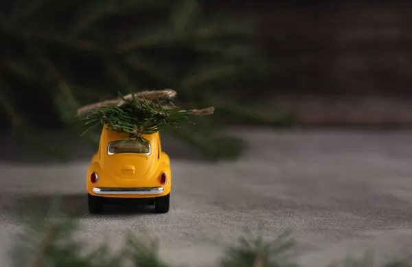 Gri arka planda ladin dalları olan sarı retro bir araba.
