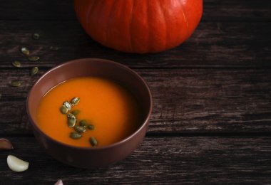 Kahverengi bir fincanda tohumlu kabak çorbası koyu ahşap bir arka planda