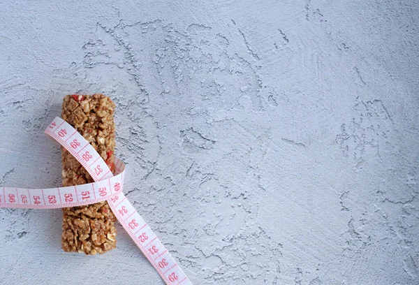 Müsli-Fitness-Riegel mit Zentimeterband auf grauem Hintergrund — Stockfoto