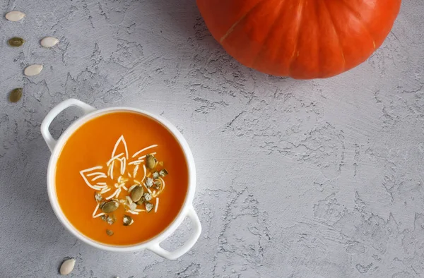 Pumpkin soup with pumpkin seeds in a white bowl on a gray background — Stock Photo, Image