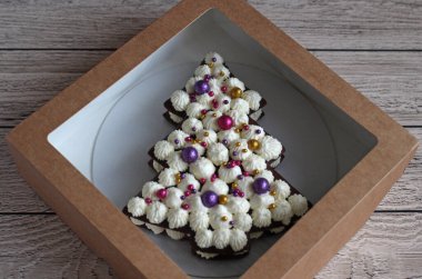 Bej arka planda bir kutuda ladin şeklinde güzel bir mini kek.