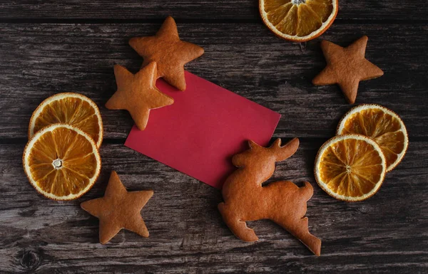 Ginger cookies in the form of deer and stars with orange slices on a wooden background with a copy space — Stock Photo, Image