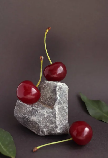 Cherries located on a heart-shaped stone on a dark background — Stock Photo, Image