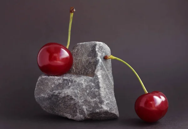 Cherries located on a heart-shaped stone on a dark background — Stock Photo, Image