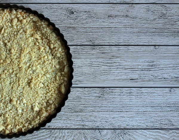 Pie crumbly with cottage cheese in black form on a wooden background — Stock Photo, Image