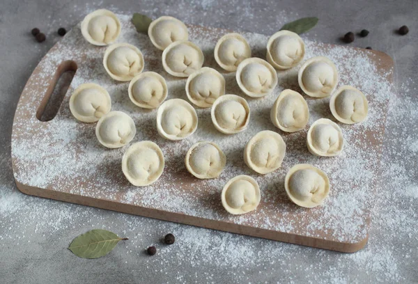 Ev yapımı hamur köfteleri un, biber ve defne yaprağı sıralarında kesim tahtasında.