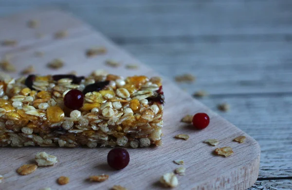 healthy cereal fitness bar with pieces of fruit and berries on a wooden background