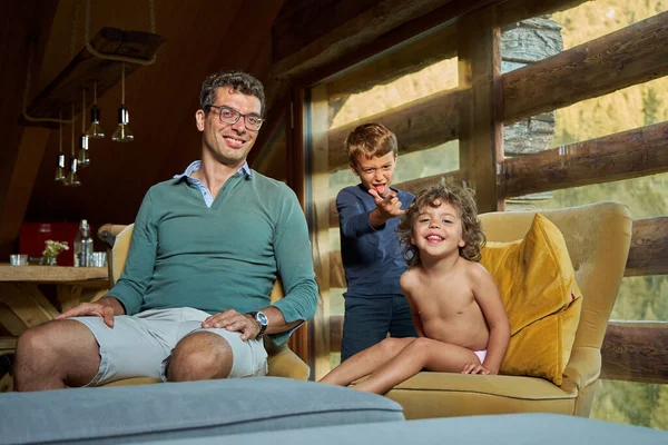 Az apa és a gyerekek egy gyönyörű faházban pihentek.. Stock Fotó