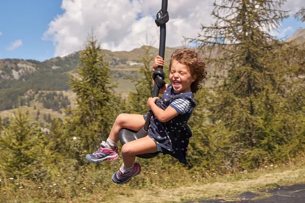 Menina bonita feliz com alta velocidade equitação em um balanço alto nas montanhas. — Fotografia de Stock