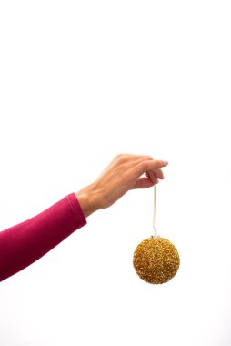 Beyaz arka planda bir Noel altın topu tutuyor.