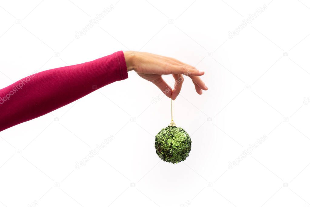 Hand holding a Christmas green ball on white background