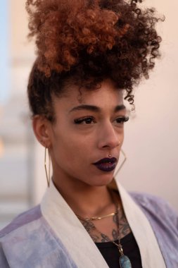 İspanya 'nın Cadiz kentinde terasta dinlenirken siyah dudaklı, kıvırcık saçlı ve kimono giyen şık siyah bir kadın.