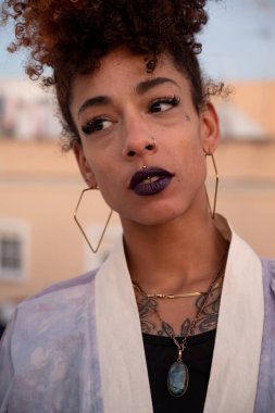 İspanya 'nın Cadiz kentinde terasta dinlenirken siyah dudaklı, kıvırcık saçlı ve kimono giyen şık siyah bir kadın.