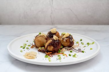 Mermer bir masanın üzerinde bir tabak takoyaki.