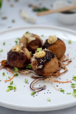 Mermer bir masanın üzerinde bir tabak takoyaki.