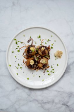 Mermer bir masanın üzerinde bir tabak takoyaki.