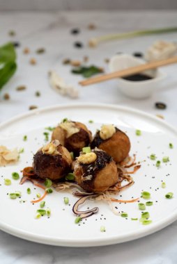 Mermer bir masanın üzerinde bir tabak takoyaki.