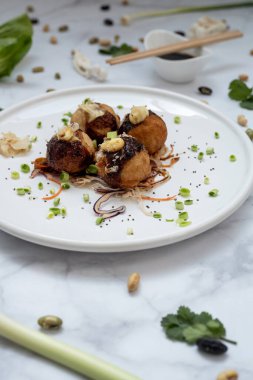 Mermer bir masanın üzerinde bir tabak takoyaki.