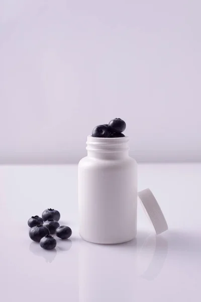 白い背景に白い瓶にブルーベリーの丸薬 — ストック写真
