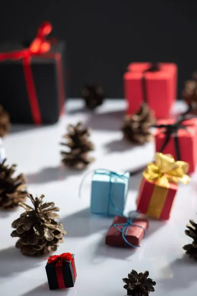 白いテーブルと暗い背景に贈り物や松のコーンと新年の静物画 — ストック写真