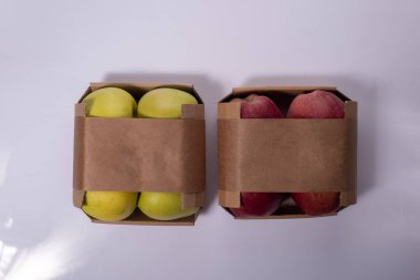 Beyaz arkaplanda sarı ve kırmızı elma paketleri.