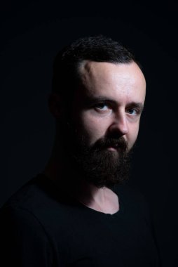 Siyah arka planda sakallı bin yılın dramatik portresi.