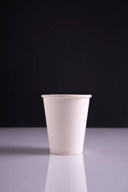 Beyaz kağıt bardaklar beyaz masa ve koyu arkaplan.