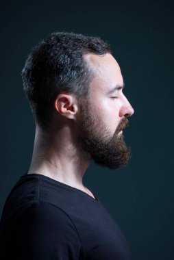 Siyah arka planda binlerce yıllık sakallı adamın dramatik portresi.