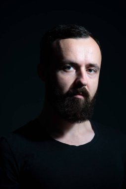 Siyah arka planda sakallı bin yılın dramatik portresi.