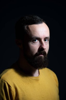 Siyah arka planda sarı kazaklı bir adamın otantik portresi..