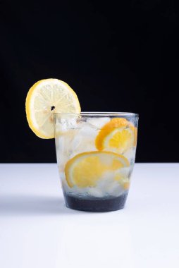 Beyaz masa ve siyah arka planda pipetle bardakta limonata. Minimalist.