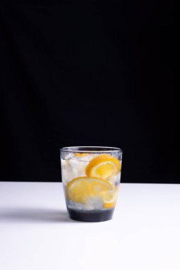 Beyaz masa ve siyah arka planda pipetle bardakta limonata. Minimalist.