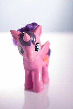 Pink sitting unicorn on a white background. Plastic toy for children. Pony or doll.