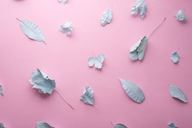 autumn pastel background blue leaves in paint on a pink background.