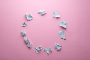 circle of autumn leaves in paint on a pink background minimal concept.